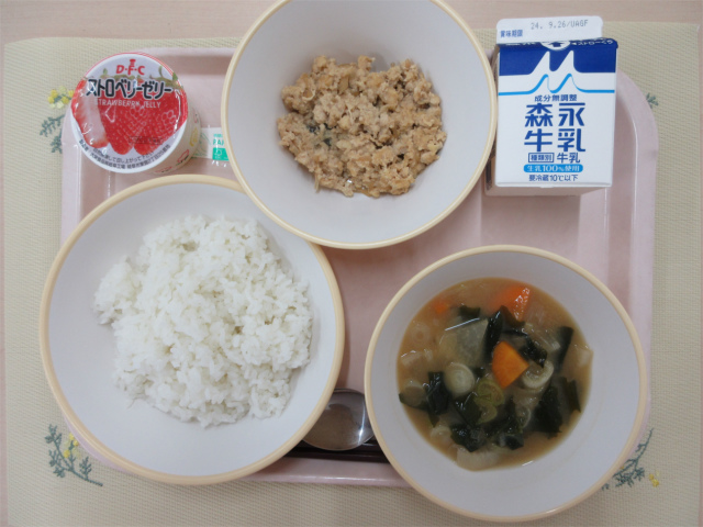 ピンクのトレーに給食が右上から反時計回りで牛乳、鶏そぼろ丼の具、いちごゼリー、ごはん、豆腐の味噌汁と並べられている写真