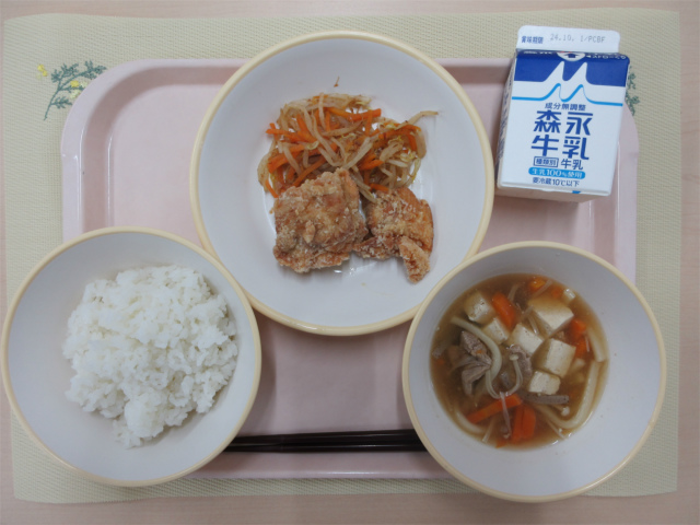 ピンクのトレーに給食が右上から反時計回りで牛乳、もやしのおかか和え、鶏肉のから揚げ、ごはん、あんかけ汁と並べられている写真