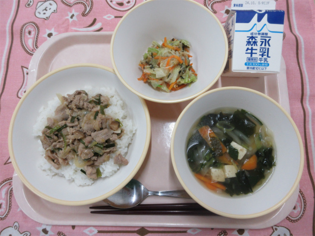 ピンクのトレーに給食が右上から反時計回りで牛乳、焼肉丼（ごはん）、わかめスープと並べられている写真