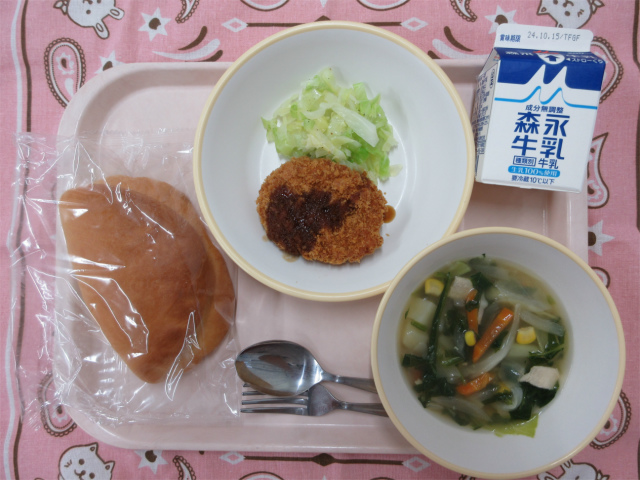 ピンクのトレーに給食が右上から反時計回りで牛乳、千切りキャベツ、コロッケ、サンドパン、野菜のスープ煮 と並べられている写真