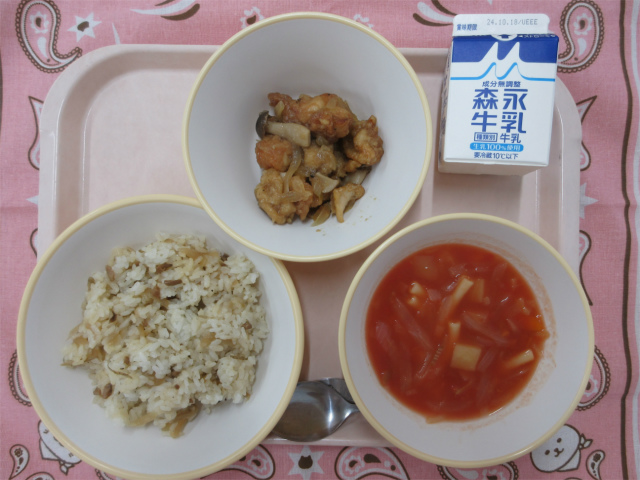 ピンクのトレーに給食が右上から反時計回りで、牛乳、鶏肉のガーリック炒め、ごぼうピラフ、ミネストローネと並べられている写真