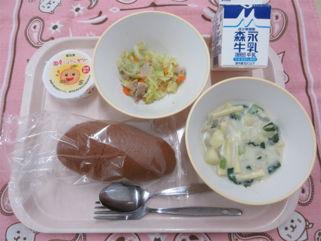 ピンクのトレーに給食が右上から反時計回りで牛乳、キャベツソテー、いよかんゼリー、黒パン 、マカロニのクリーム煮と並べられている写真