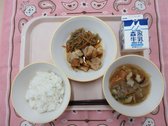 ピンクのトレーに給食が右上から反時計回りで牛乳、きんぴらごぼう、鶏肉の甘酢だれ、ごはん、のっぺい汁と並べられている写真