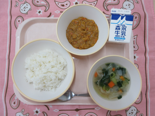 ピンクのトレーに給食が右上から反時計回りで牛乳、ドライカレー、ごはん、野菜スープと並べられている写真