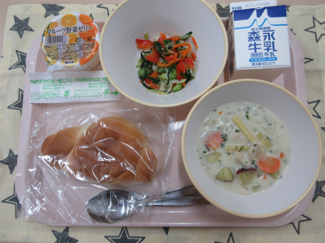 ピンクのトレーに給食が右上から反時計回りで牛乳、カラフルサラダ、フルーツ野菜ゼリー、ロールパン、さつまいものクリーム煮と並べられている写真