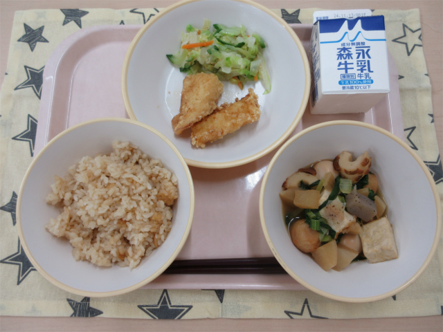 ピンクのトレーに給食が右上から反時計回りで牛乳、うま塩キャベツ、いかの吉野揚げ、茶飯、おでんと並べられている写真