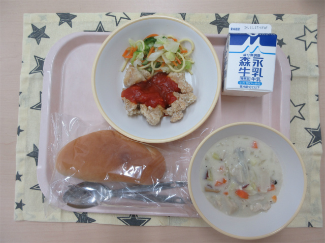 ピンクのトレーに給食が右上から反時計回りで牛乳、ミックスサラダ、鶏肉のサルサソース、コッペパン、秋の味覚シチューと並べられている写真