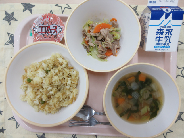 ピンクのトレーに給食が右上から反時計回りで牛乳、豚肉とキャベツのペペロンチーノ炒め、ココアムース、カレーピラフ、コンソメスープと並べられている写真