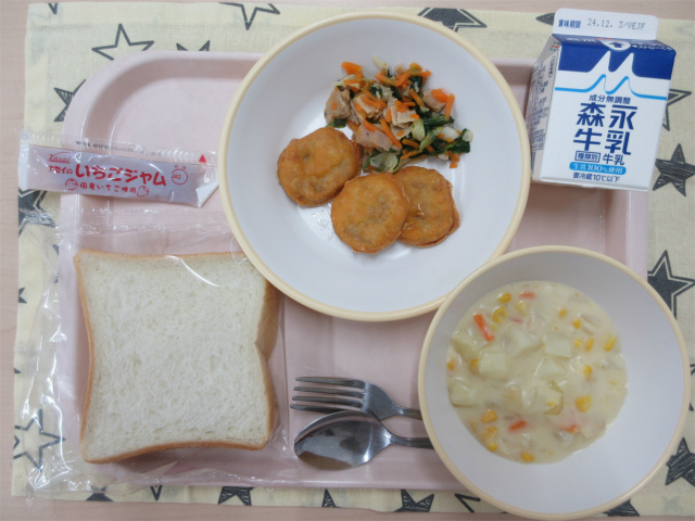 ピンクのトレーに給食が右上から反時計回りで牛乳、ほうれんそうソテー、チキンナゲット、いちごジャム、食パン、コーンシチューと並べられている写真