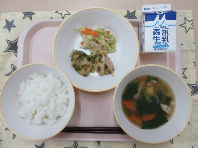 ピンクのトレーに給食が右上から反時計回りで牛乳、野菜のごま炒め、鶏肉のねぎ塩焼き、ごはん、あんかけ汁と並べられている写真