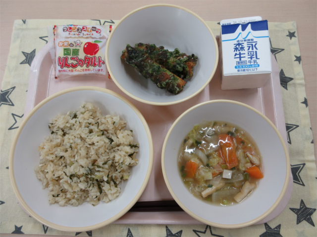 ピンクのトレーに給食が右上から反時計回りで牛乳、ちくわの磯辺揚げ、りんごタルト、鶏菜めし、白菜のとろみ汁と並べられている写真