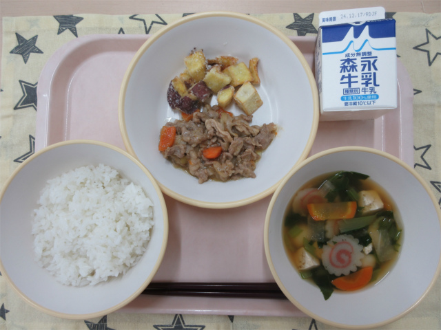 ピンクのトレーに給食が右上から反時計回りで牛乳、さつまいものコロコロ揚げ、豚肉のみそ炒め、ごはん、白玉汁と並べられている写真