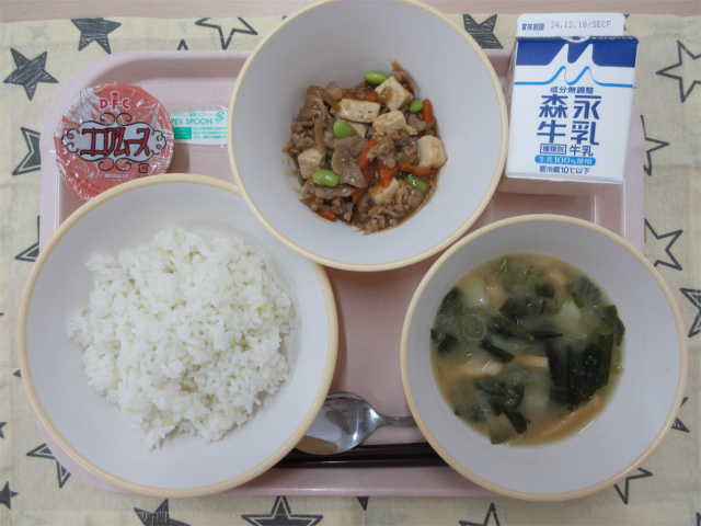 ピンクのトレーに給食が右上から反時計回りで牛乳、肉豆腐あんかけ丼の具 、ココアムース、ごはん、じゃがいもの味噌汁と並べられている写真