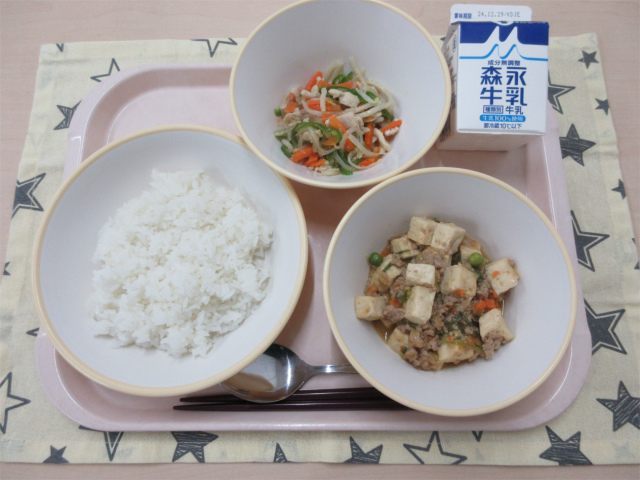 ピンクのトレーに給食が右上から反時計回りで牛乳、春雨の中華炒め、ごはん、麻婆豆腐丼の具と並んでいる写真