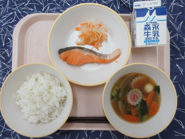 ピンクのトレーに給食が右上から反時計回りで牛乳、鮭の塩焼きと紅白ゆずなます、ごはん、白玉雑煮と並べられている写真