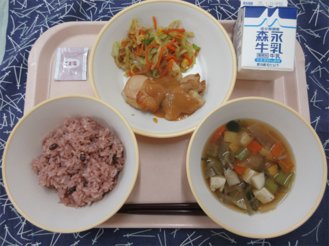 ピンクのトレーに給食が右上から反時計回りで牛乳、鶏肉の味噌焼きとカラフルおひたし、ごま塩、赤飯、けんちん汁と並べられている写真