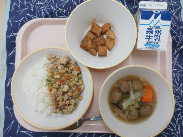 ピンクのトレーに給食が右上から反時計回りで牛乳、スパイシーポテト、ガパオライス、白菜と肉団子のスープと並べられている写真