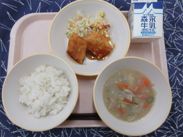 ピンクのトレーに給食が右上から反時計回りで牛乳、いかのかりん揚げとキャベツのごまマヨサラダ、ごはん、豚汁と並べられている写真