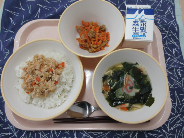 ピンクのトレーに給食が右上から反時計回りで牛乳、にんじんとヤーコンのしりしり、とりそぼろ丼、わかめスープと並べられている写真