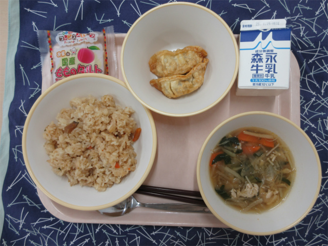 ピンクのトレーに給食が右上から反時計回りで牛乳、揚げ餃子、ももタルト、中華炊き込みごはん、切り干し大根のピリ辛スープと並べられている写真