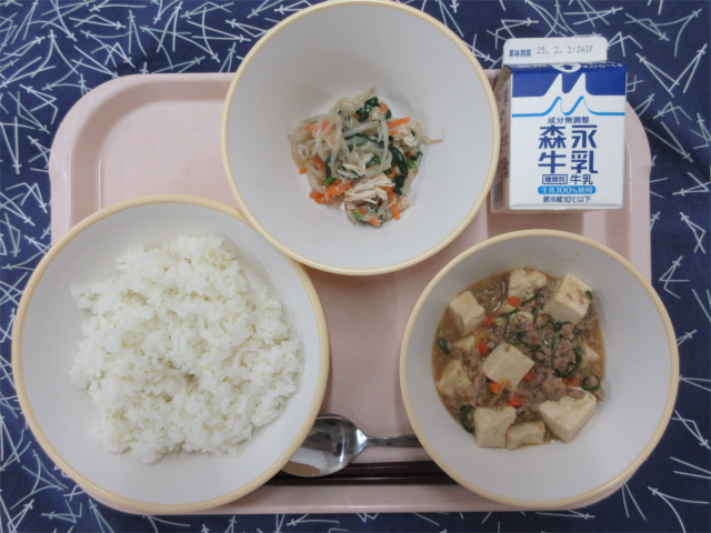 ピンクのトレーに給食が右上から反時計回りで牛乳、鶏肉と野菜のナムル、ごはん、麻婆豆腐丼の具と並べられている写真