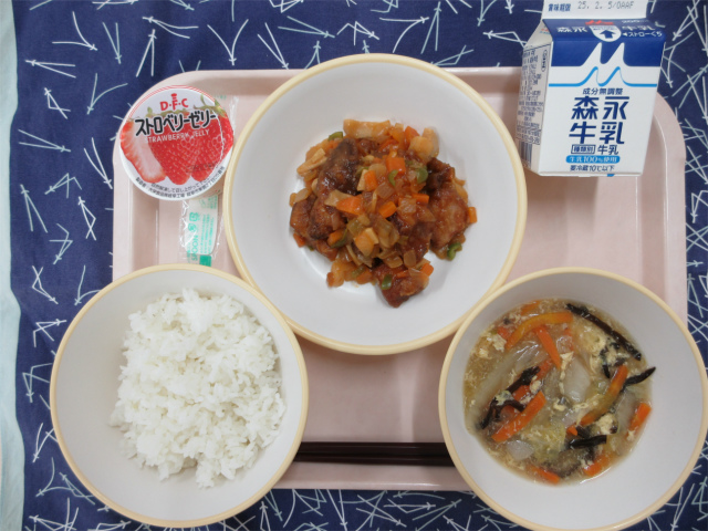 ピンクのトレーに給食が右上から反時計回りで牛乳、酢豚、いちごゼリー、ごはん、中華たまごスープと並べられている写真