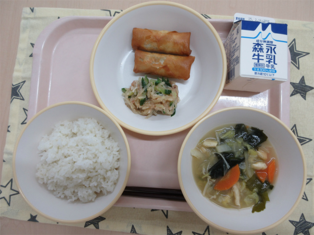 ピンクのトレーに給食が右上から反時計回りで牛乳、春巻きと大根の梅おかか和え、ごはん、冬野菜の味噌汁と並べられている写真