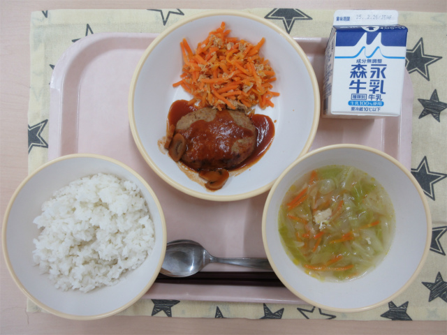 ピンクのトレーに給食が右上から反時計回りで牛乳、デミグラスハンバーグとツナとにんじんのソテー、ごはん、スコッチブロスと並べられている写真