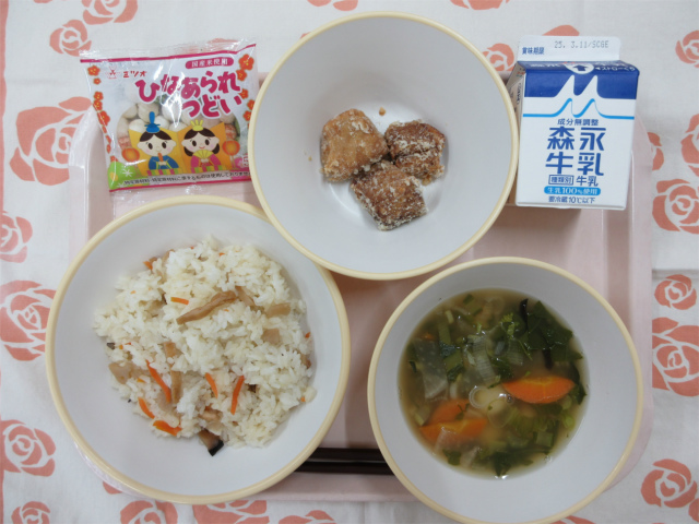 ピンクのトレーに給食が右上から反時計回りで牛乳、まぐろの竜田揚げ、ひなあられ、ちらし寿司、白玉汁と並べられている写真