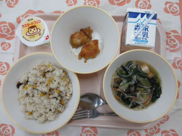 ピンクのトレーに給食が右上から反時計回りで牛乳、タンドリーチキン、カスタードプリン、ペッパーライス、ビーフンスープと並べられている写真