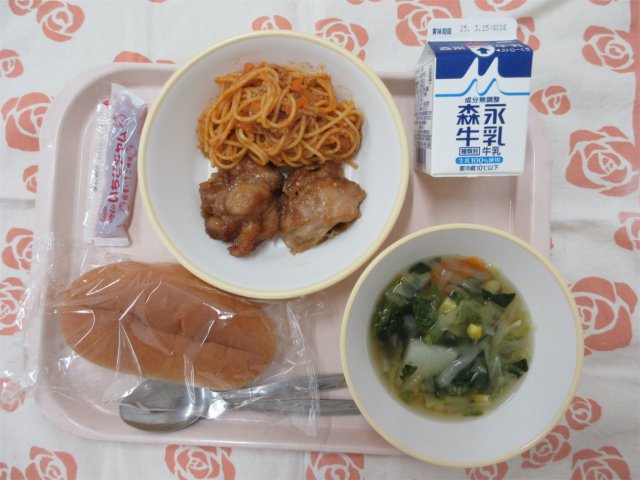 ピンクのトレーに給食が右上から反時計回りで牛乳、モチコチキンとスパゲッティミートソース、いちごジャム、コッペパン、野菜スープと並べられている写真