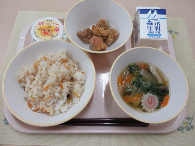 ピンクのトレーに給食が右上から反時計回りで牛乳、鶏肉のから揚げ、いよかんゼリー、ちらし寿司、すまし汁と並べられている写