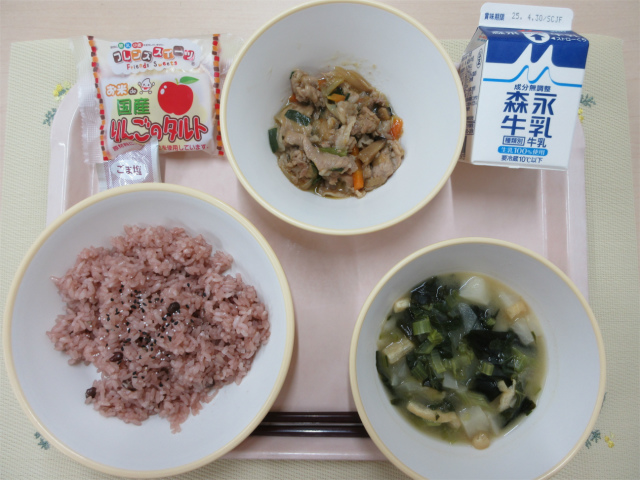 ピンクのトレーに給食が右上から反時計回りで牛乳、肉野菜炒め、りんごタルト、赤飯、かぶの味噌汁と並べられている写真
