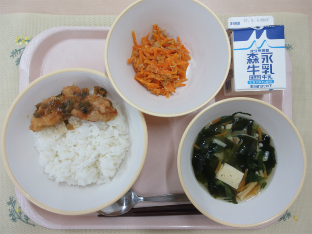 ピンクのトレーに給食が右上から反時計回りで牛乳、にんじんしりしり、甘辛からあげ丼、わかめスープと並べられている写真