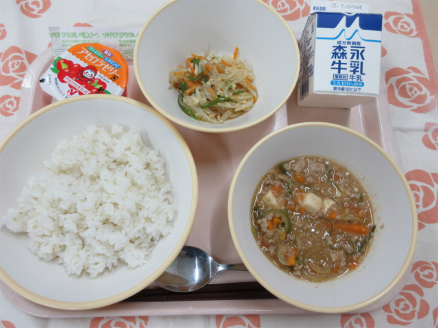 ピンクのトレーに給食が右上から反時計回りで牛乳、春雨の中華炒め、アセロラゼリー、ごはん、麻婆豆腐と並べられている写真