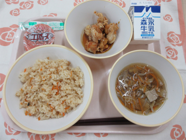 ピンクのトレーに給食が右上から反時計回りで牛乳、鶏肉のかりん揚げ、ココアムース、かやくごはん、沢煮椀と並べられている写真