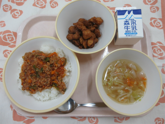 ピンクのトレーに給食が右上から反時計回りで牛乳、じゃがじゃが、タコライス（ごはん）、ABCスープと並べられている写真