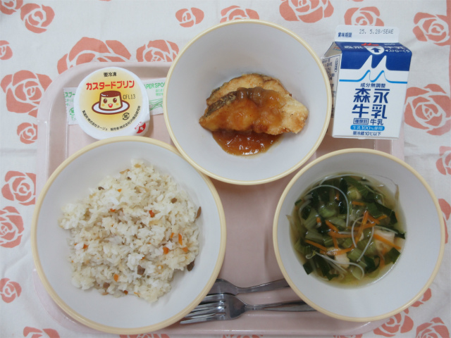 ピンクのトレーに給食が右上から反時計回りで牛乳、白身魚のバーベキューソース、カスタードプリン、ガーリックライス、ビーフンスープと並べられている写真