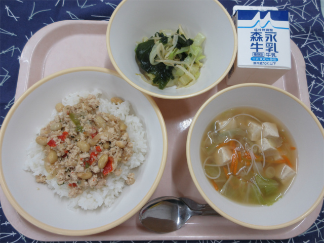 ピンクのトレーに給食が右上から反時計回りで牛乳、海藻サラダ、ガパオライス（ごはん）、ビーフンスープと並べられている写真