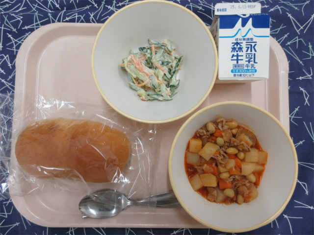 ピンクのトレーに給食が右上から反時計回りで牛乳、きゅうりのごまマヨサラダ、ソフトフランスパン、ポークビーンズと並べられている写真