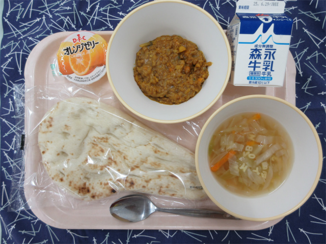 ピンクのトレーに給食が右上から反時計回りで牛乳、ドライカレー、オレンジゼリー、ナン、ABCスープと並べられている写真