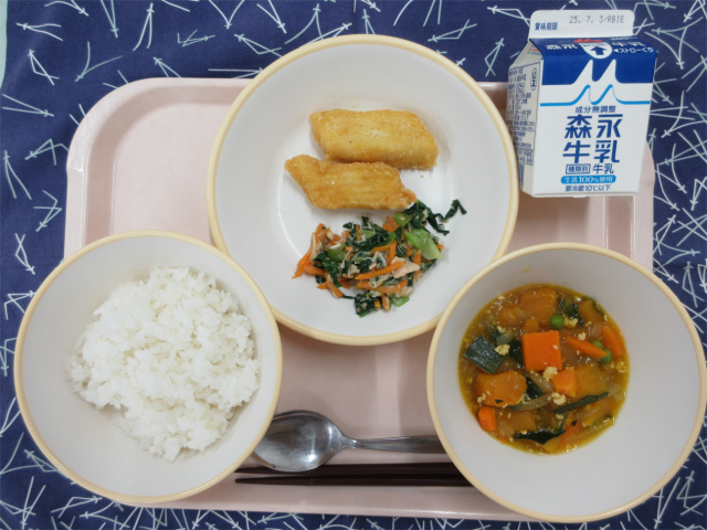 ピンクのトレーに給食が右上から反時計回りで牛乳、いかのカレー揚げと小松菜と鶏ささみの和え物、ごはん、かぼちゃのそぼろ煮と並べられている写真