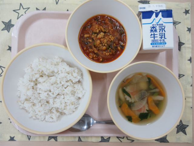 ピンクのトレーに給食が右上から反時計回りで牛乳、トマトとひき肉のアジアンライスの具、麦入りごはん、白玉スープと並べられている写真