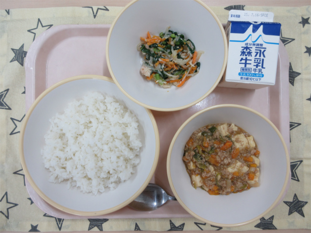 ピンクのトレーに給食が右上から反時計回りで牛乳、鶏肉と野菜のナムル、ごはん、麻婆豆腐丼の具と並べられている写真