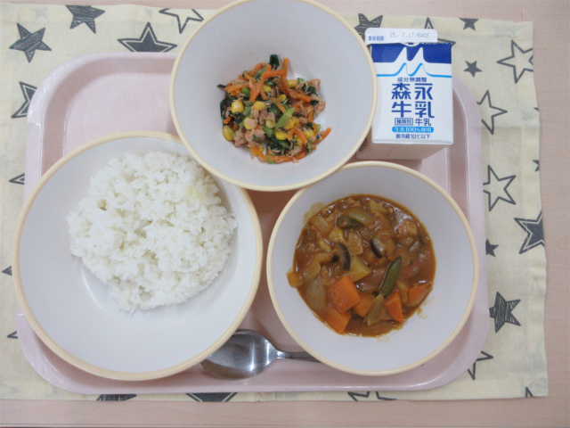 ピンクのトレーに給食が右上から反時計回りで牛乳、こまツナサラダ、ごはん、夏野菜のカレーと並べられている写真