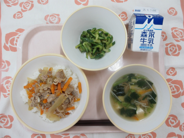 ピンクのトレーに給食が右上から反時計回りで牛乳、ピリ辛きゅうり、豚丼（ごはん）、わかめとえのきのスープと並べられている写真