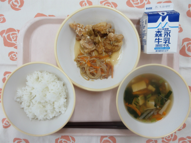 ピンクのトレーに給食が右上から反時計回りで牛乳、油淋鶏、もやしのおかか和え、ごはん、あんかけ汁と並べられている写真