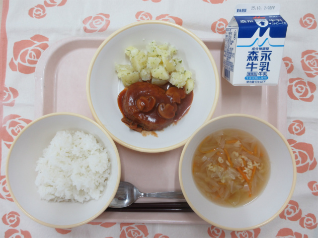 ピンクのトレーに給食が右上から反時計回りで牛乳、粉ふきいも、デミグラスハンバーグ、ごはん、ABCスープと並べられている写真