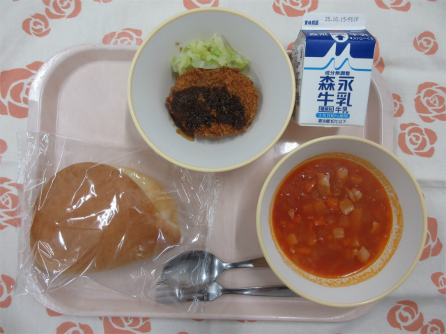 ピンクのトレーに給食が右上から反時計回りで牛乳、コロッケ、千切りキャベツ、サンドパン、ミネストローネと並べられている写真