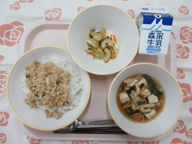 ピンクのトレーに給食が右上から反時計回りで牛乳、キャベツとちくわの炒め物、鶏そぼろ丼（もち麦入りごはん）、すまし汁と並べられている写真